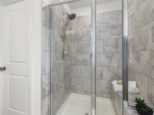 Contemporary bathroom shower with glass door and gray tile walls, perfect for elegant home interiors.
