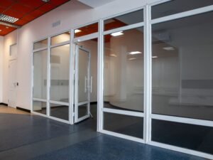 Spacious modern office room with glass walls and open door, ideal for office space or business settings.