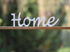 Elegant wooden 'Home' sign against a blurred green background, perfect for cozy decor themes.
