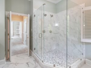 Spacious luxury bathroom featuring a contemporary marble shower with glass doors and elegant interior design.