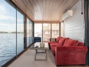 Stylish living room with red sofa and lake view through large glass doors.