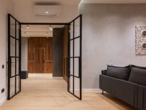 Interior of modern bright house with open doors to hallway near sofa with pillows